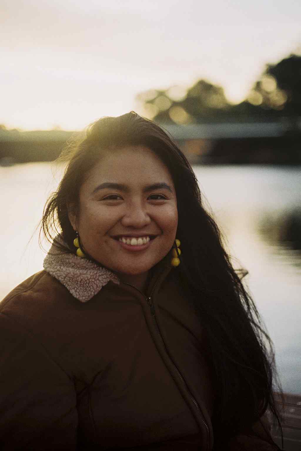Smiling artist Alyssa Powell-Ascura with a sunset background. Photograph taken by Louis Bullock on film.